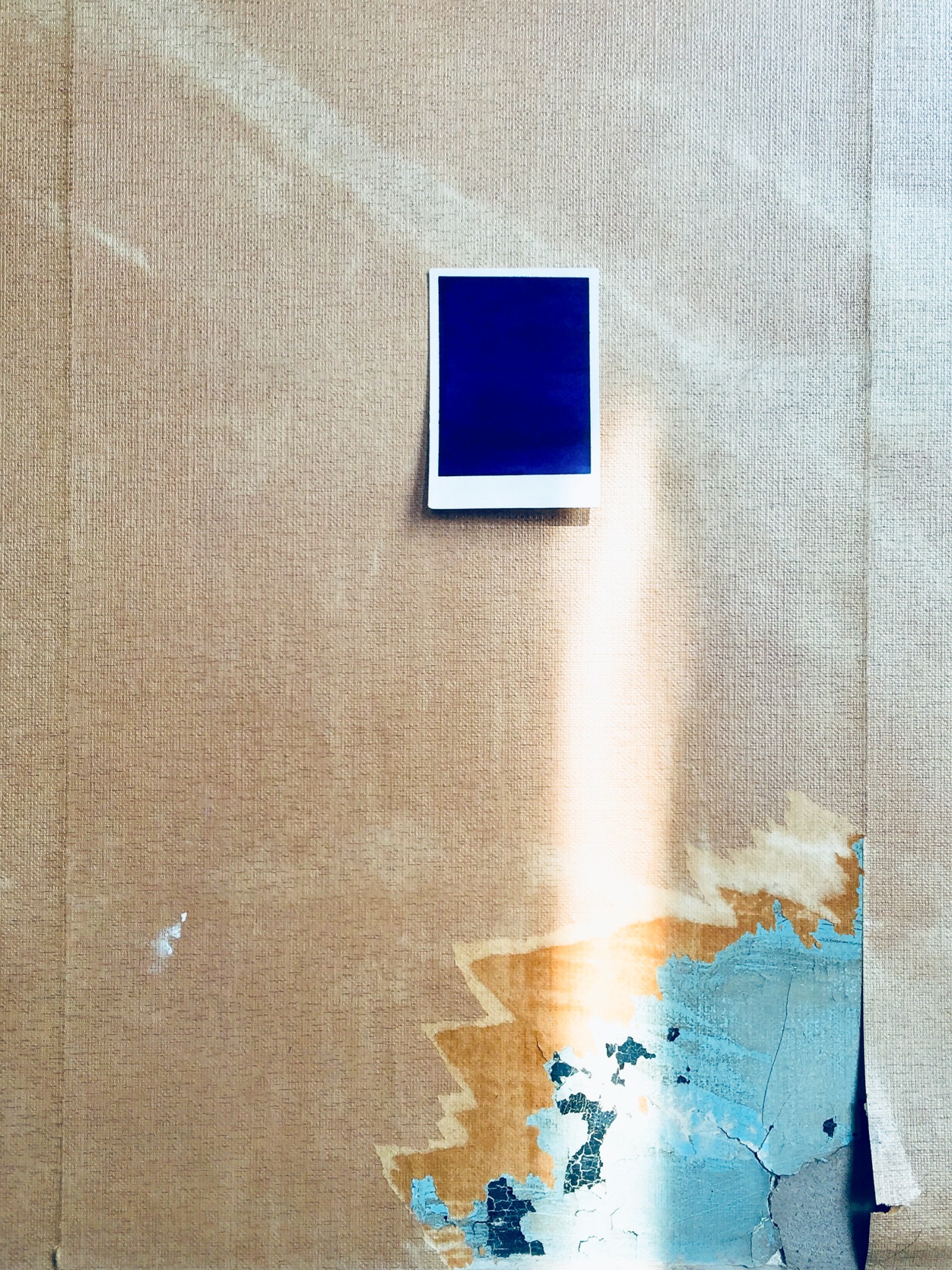 A small blue monochrome pinned to an off-white wall