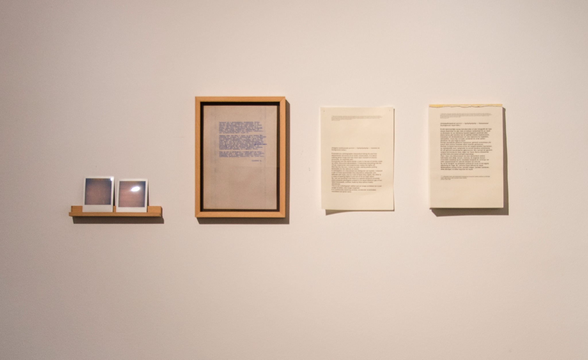 Installation detail showing the Polaroids, typewritten text, transcription and translation