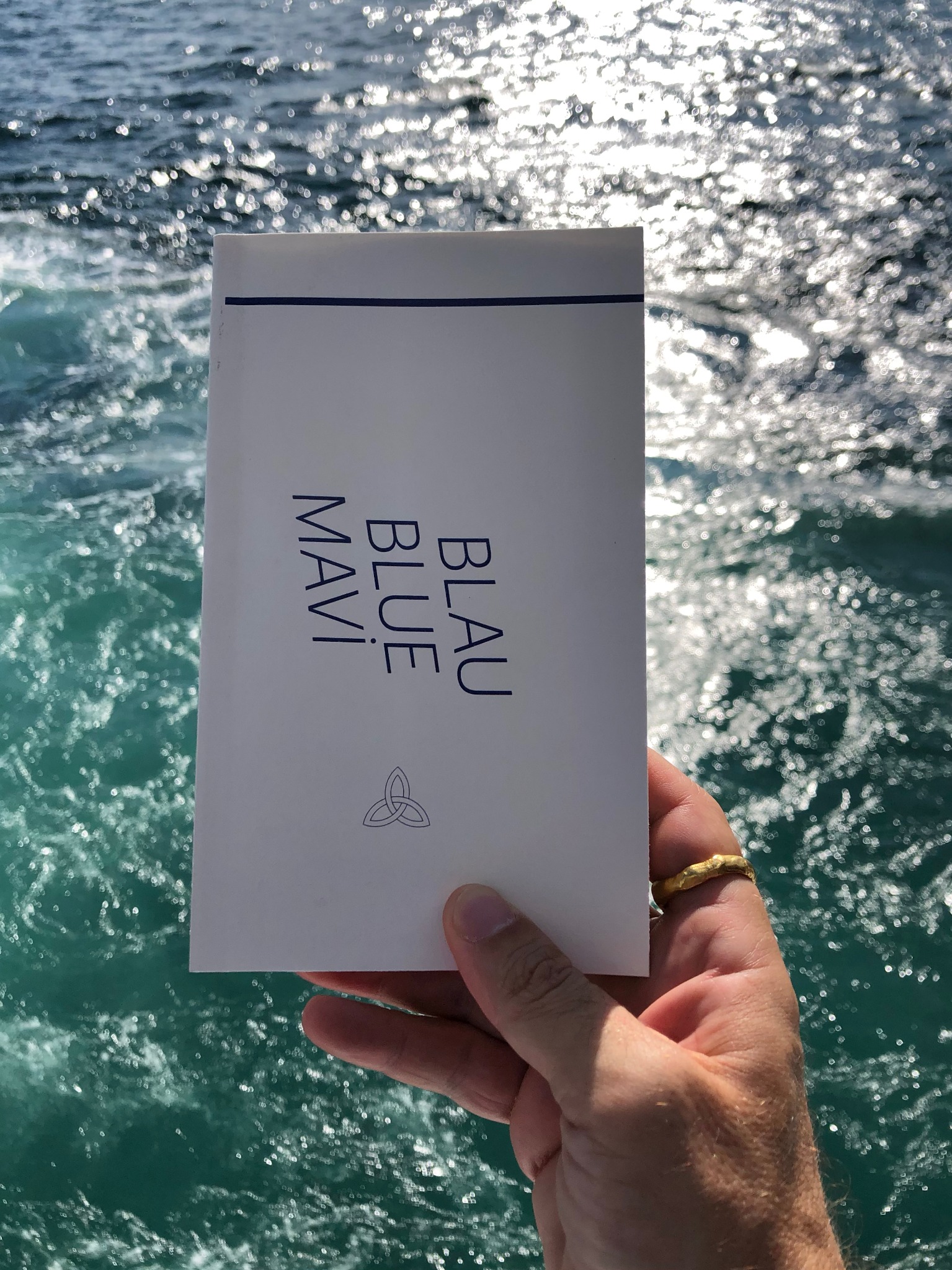 Mavi Blue Blau held against a seascape