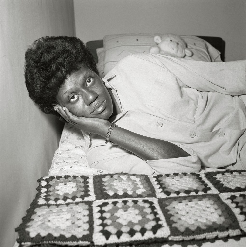 A woman reclining on a bed and looking toward the camera